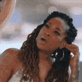 a woman with dreadlocks and hoop earrings looks at something