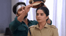a man is putting a hat on top of a woman 's head .