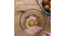 a person is cracking an egg into a glass bowl .