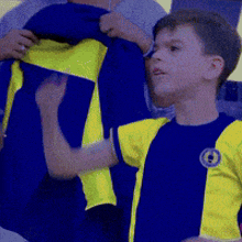 a boy wearing a blue and yellow shirt with the letter o on the front
