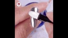 a person is using a brush to paint a nail with silver powder .
