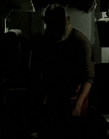 a man with a red sash around his waist is standing in the dark
