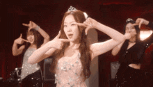 a woman in a pink dress with a tiara on her head is dancing with two other women