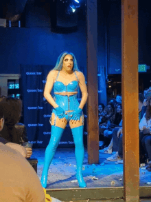 a drag queen is standing in front of a queer bar sign
