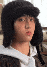 a person wearing a furry hat and a white hoodie