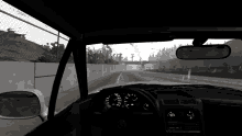 a car is driving down a highway with a fence in the background and a rear view mirror