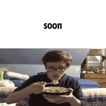 a boy with glasses is eating a bowl of cereal with the word soon behind him