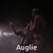 a man in a plaid shirt stands next to another man with the name auglie written on the bottom