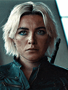 a close up of a woman 's face with blonde hair and a black jacket .