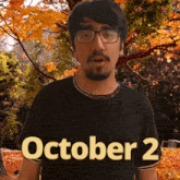 a man wearing glasses and a black shirt that says october 2 on it