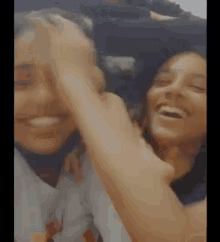 a couple of girls are laughing and hugging each other in a blurry photo .