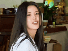 a woman with long black hair and a white shirt smiles for the camera