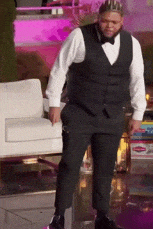 a man wearing a tuxedo and a crown is standing in front of a chair