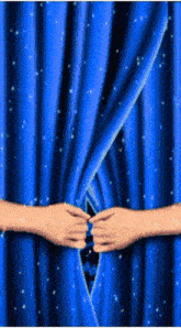 a person is opening a blue curtain with a hole in the middle