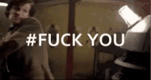 a man in a suit is standing in front of a light with the words # fuck you written on it .