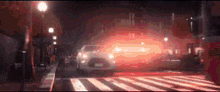 a car is driving down a street at night with a red light coming out of it .