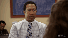 a man in a plaid shirt and tie talks to a woman with netflix written on the bottom