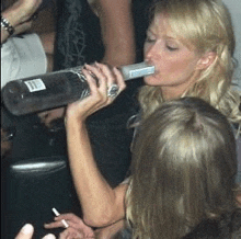 a woman is drinking a bottle of vodka from a straw .