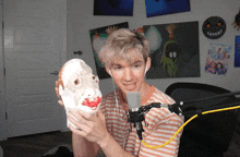 a man in a striped shirt is holding a foam mask in front of a microphone