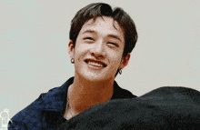 a young man is smiling and looking at the camera while wearing earrings and a necklace .