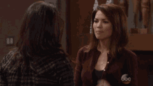 a woman is pointing at another woman while wearing a sweater with the abc logo on it