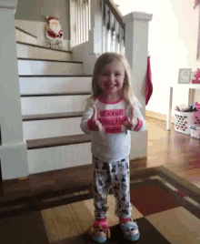 a little girl wearing a shirt that says it 's full being the santa giving a thumbs up