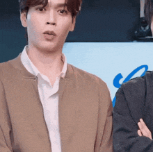 a man in a brown jacket is standing next to another man