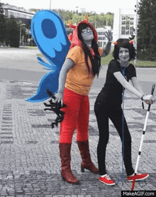 two women dressed in costumes are standing next to each other on a sidewalk