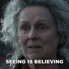 a woman with gray hair has the words seeing is believing above her