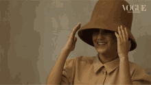 a woman wearing a hat with the word vogue on the bottom right