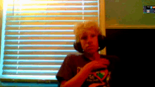 a man wearing headphones and a shirt that says ' rv ' on it stands in front of a window