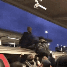 a man is sitting on the roof of a building with a camera hanging from the ceiling .