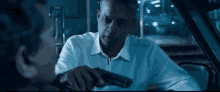 a man in a white shirt is holding a gun to another man