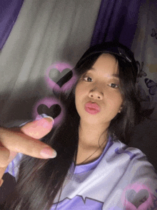 a girl wearing a hat and a purple shirt is taking a picture of herself