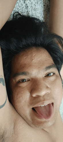a man with his tongue out has a tattoo on his arm