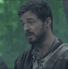 a man with a beard and a rope around his neck is looking at something