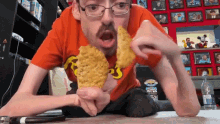 a man wearing a reese 's t-shirt is eating two pieces of fried chicken