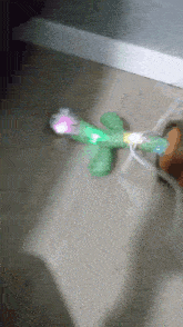 a green toy with a light on it is on the floor next to a person 's foot
