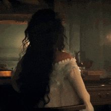 a woman in a white shirt is standing in a dark room