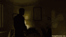 a silhouette of a man standing in a dark room with a lamp in the background .