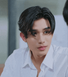 a close up of a young man wearing a white shirt and earrings .