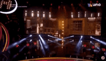 a man is standing on a stage in a dark room with a lot of lights .