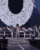 a group of dancers perform on a stage in front of a large u