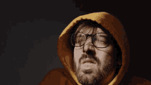 a man with glasses and a beard wears a yellow hoodie
