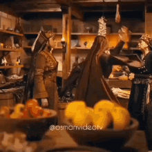 a group of people standing around a table with a bowl of fruit in the foreground and a caption that says @osmanvideotv