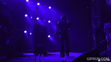 a man playing a guitar on a stage with purple lights and a gifrun.com logo
