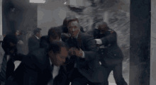 a group of men in suits and ties are fighting in a hallway .