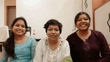 three women are posing for a picture and one of them is wearing a blue shirt