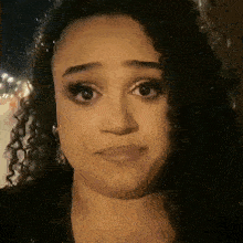 a close up of a woman 's face with curly hair making a sad face