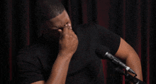 a man in a black shirt is covering his face in front of a microphone that has the letter n on it